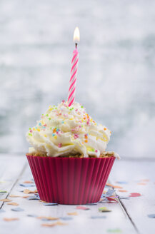 Cupcake mit brennenden Kerzen und Konfetti auf Holz - ODF000933