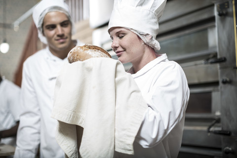 Bäckerin freut sich über frisch gebackenes Brot aus dem Ofen, lizenzfreies Stockfoto