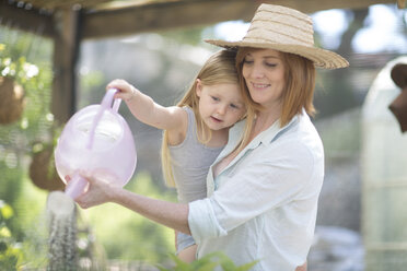 Portrait of woman and little daughter watering plants with watering can - ZEF004065