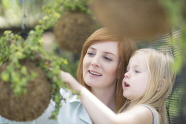 Portrait of woman and little daughter looking at plant - ZEF004072