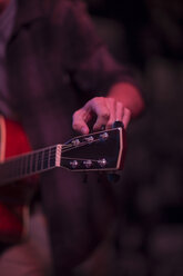 Männerhand stimmt eine akustische Gitarre - ZEF003556
