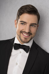 Portrait of smiling man wearing dinner jacket and bow - SHKF000107