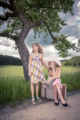 Germany, Bavaria, Girls with old suitcase waiting at roadside - VTF000383