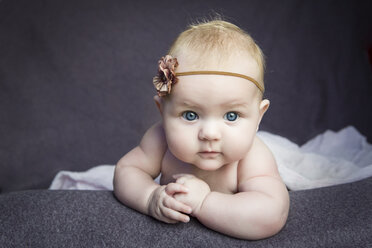 Kleines Mädchen mit Haarband und Blume auf einer Decke liegend - JTLF000023
