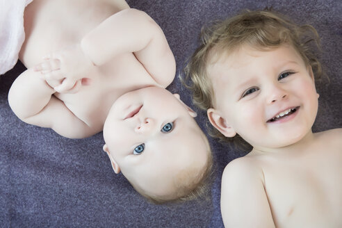 Portrait of baby girl and little brother lying on blanket - JTLF000026
