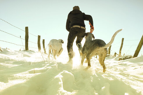 Deutschland, Bergisches Land, Mann läuft mit Hunden in Winterlandschaft - ONF000738