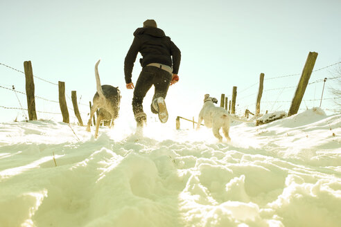 Deutschland, Bergisches Land, Mann läuft mit Hunden in Winterlandschaft - ONF000739