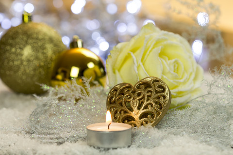 Weihnachtsdekoration mit Teelicht, Weihnachtskugeln und Rosenblüten auf Kunstschnee, lizenzfreies Stockfoto