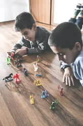 Zwei Jungen spielen zu Hause mit Miniaturfiguren auf dem Boden - DEGF000102