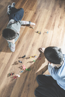 Zwei Jungen spielen zu Hause mit Miniaturfiguren auf dem Boden - DEGF000104