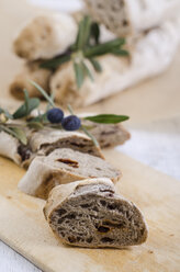 Selbstgebackenes Baguette mit Oliven und getrockneten Tomaten auf Holzbrettchen - ODF000976