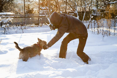 Mann fotografiert und spielt mit Hund im Schnee - NDF000507