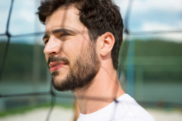 Young man at net of beach volleyball field - WESTF020675