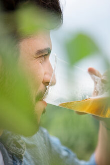 Young man drinking beer from plastic cup outdoors - WESTF020686