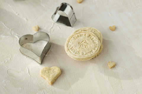 Home-baked motif cookies and two heart shaped metal cookie cutters on light wood stock photo