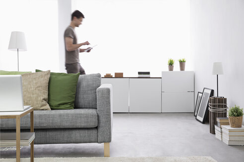 Young man using digital tablet in his living room - PDF000674