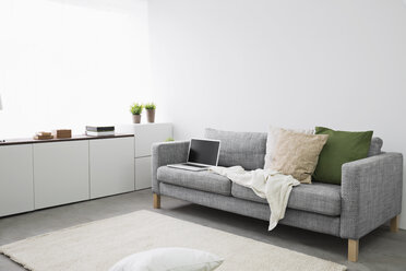 Geöffneter Laptop auf der Couch im modernen Wohnzimmer - PDF000658