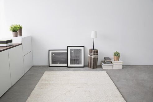 Sideboard, Bilderrahmen, Bücherstapel, Teppich und Tischlampe in einem modernen Wohnzimmer - PDF000673