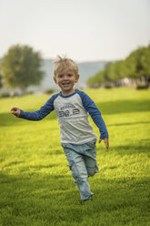 Fröhlicher Junge läuft auf der Wiese - PAF001199