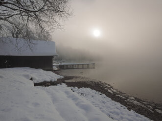 Deutschland, Kochel am See, schneebedecktes Bootshaus am Ufer des Kochelsees - LAF001381