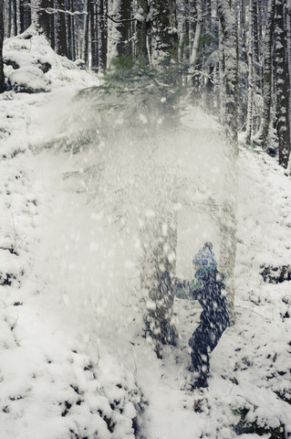 Germany, Bavaria, Berchtesgadener Land, snow falling on boy in woods stock photo