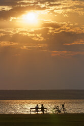 Austria, Burgenland, Illmitz, Lake Neusiedl, People sitting on bench at sunset - SIEF006351