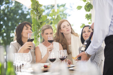 Kellner präsentiert den Frauen bei einer Weinprobe eine Flasche Rotwein - ZEF003210
