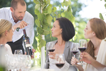 Kellner präsentiert den Frauen bei einer Weinprobe eine Flasche Rotwein - ZEF003212