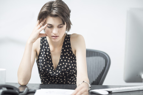 Frustrierte Geschäftsfrau sitzt am Schreibtisch, lizenzfreies Stockfoto