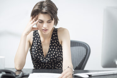 Frustrierte Geschäftsfrau sitzt am Schreibtisch - ZEF003033