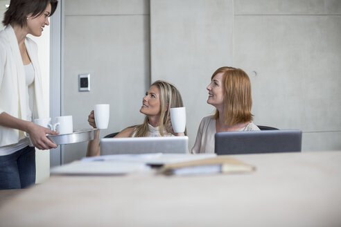 Drei Geschäftsfrauen trinken Kaffee in einem Konferenzraum - ZEF003047