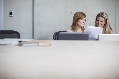 Two businesswomen with laptop and documents in conference room - ZEF003048