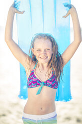 Girl on the beach smiling and holding a lilo - ZEF003303