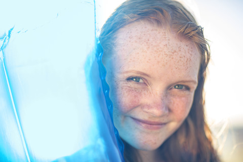 Porträt eines lächelnden Mädchens am Strand mit einer Luftmatratze, lizenzfreies Stockfoto