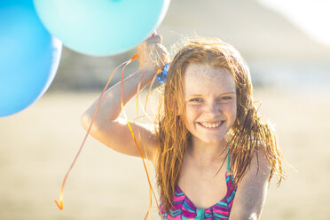 Girl on the beach smiling and holding balloons - ZEF003306