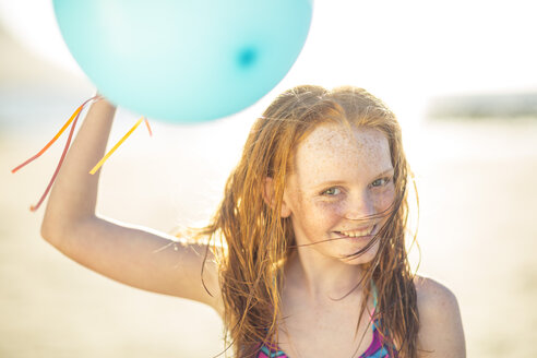 Mädchen am Strand lächelnd und hält Ballon - ZEF003307