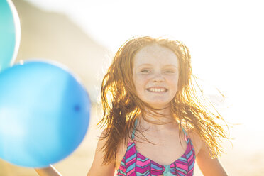 Mädchen am Strand lächelnd und hält Luftballons - ZEF003308