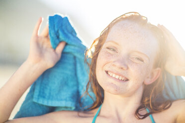 Portrait of smiling girl on the beach drying her hair with a beach towel - ZEF003313
