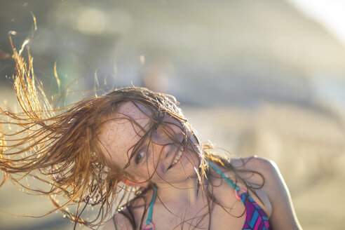 Mädchen am Strand lächelnd und ihr Haar im Wind schwingend - ZEF003314