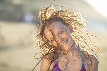 Mädchen am Strand lächelnd und ihr Haar im Wind schwingend - ZEF003315
