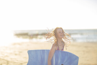 Mädchen am Strand lachend und ein Boogie Board haltend - ZEF003317