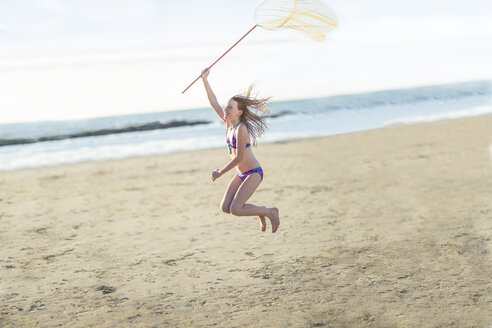 Glückliches Mädchen am Strand, das mit einem Schmetterlingsnetz springt - ZEF003318