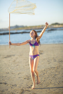 Glückliches Mädchen am Strand, das mit einem Schmetterlingsnetz läuft - ZEF003319