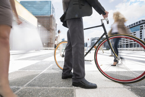 Geschäftsmann zu Fuß mit Fahrrad zwischen einer Menschenmenge in einer Stadt - ZEF003972