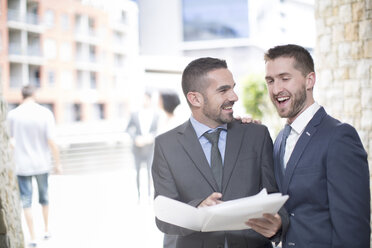 Happy gay couple with business suits looking at papers - ZEF002891