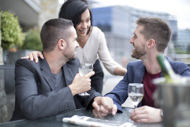 Gay couple sharing meal with a friend and drinking wine - ZEF002893