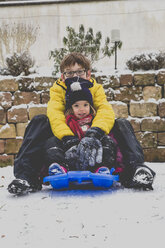 Brother and his little sister sitting on a sledge - LVF002557