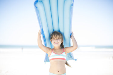 Smiling girl on beach holding a lilo - ZEF003336
