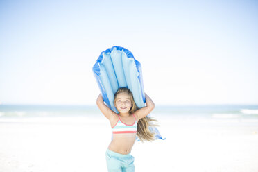 Smiling girl on beach holding a lilo - ZEF003339