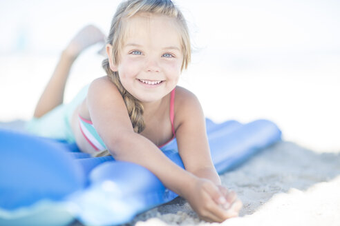Lächelndes Mädchen am Strand auf einer Luftmatratze liegend - ZEF003347